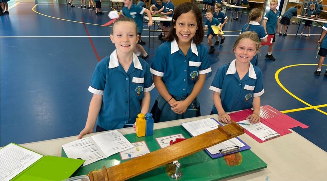 Students presenting a hands on learning display with materials and measurement equipment during a school showcase