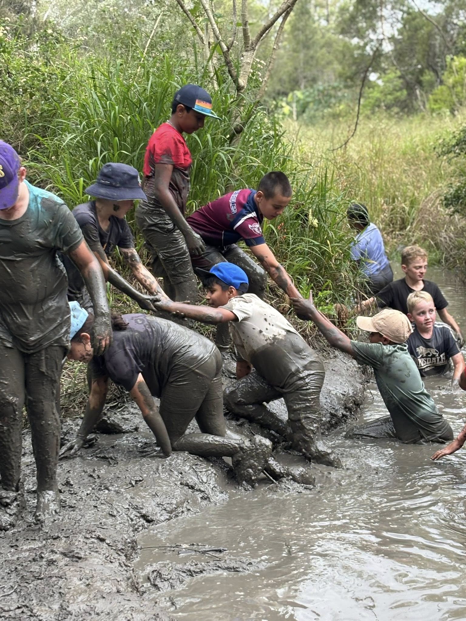 students helping each other out of mud pitt
