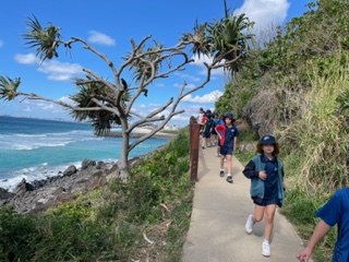 students walking outside on footpath with ocean view in background
