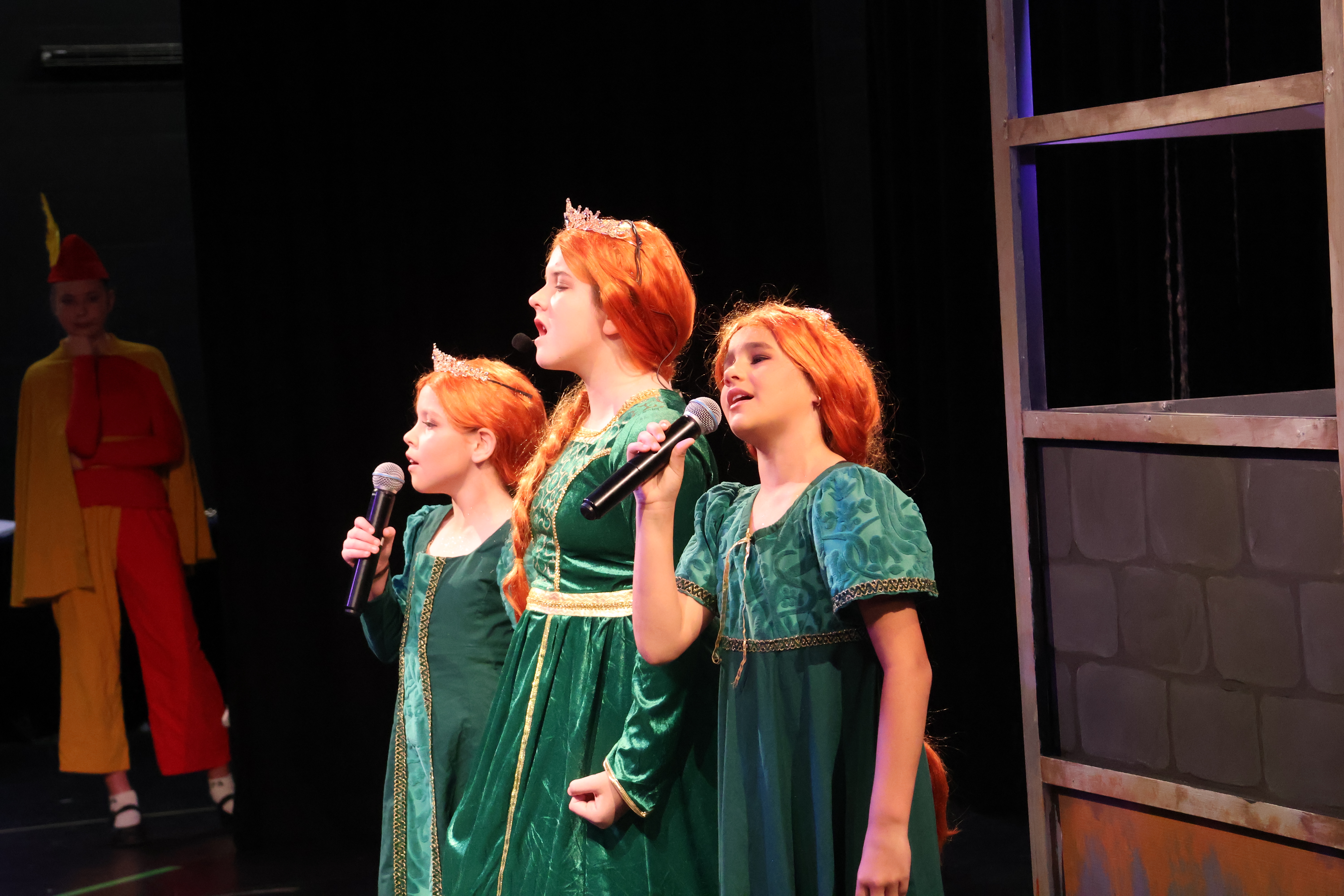 3 girls dressed as Fiona from Shrek musical on stage singing